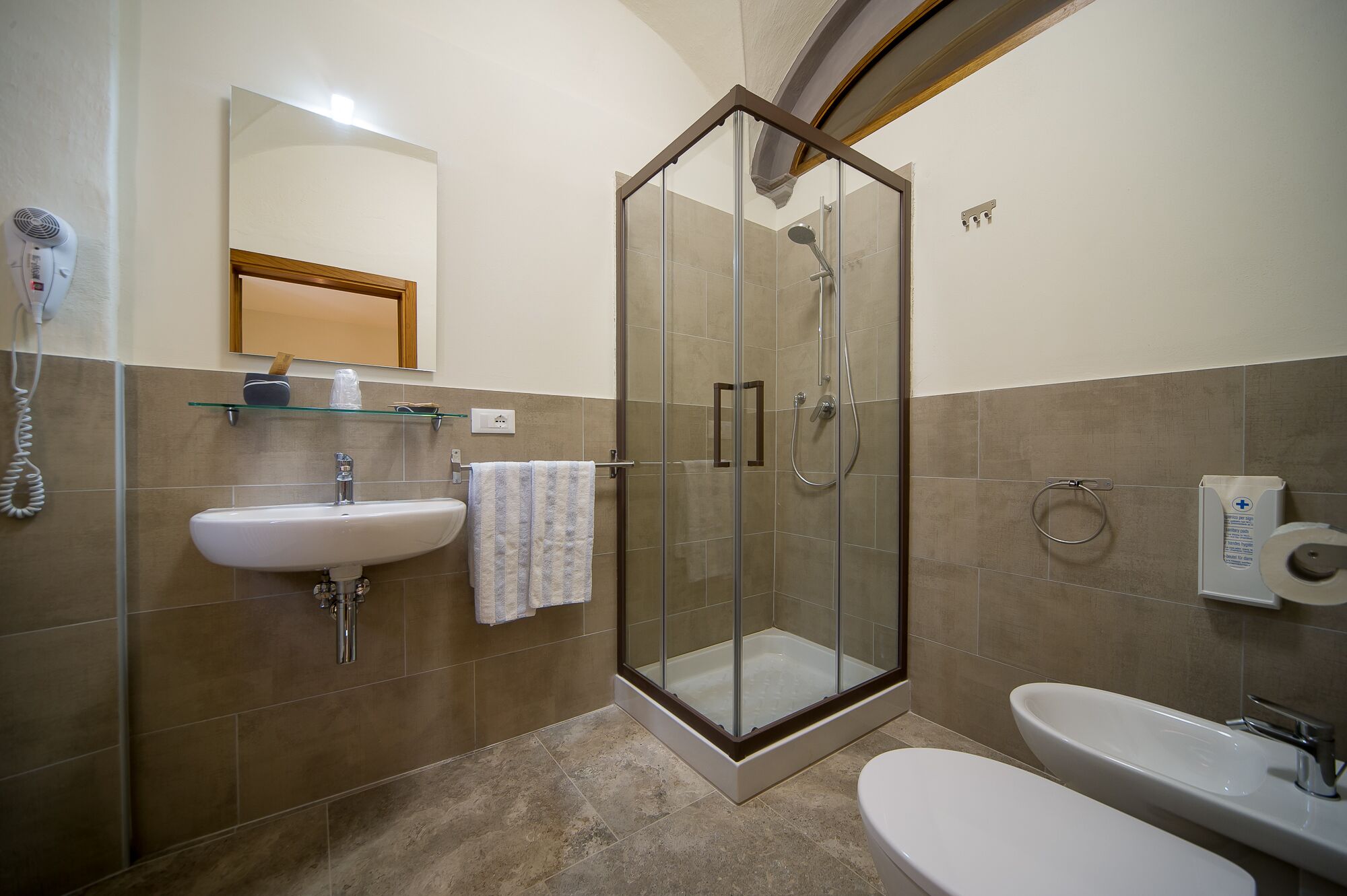 A modern bathroom with a glass-enclosed shower, a sink, and a toilet.