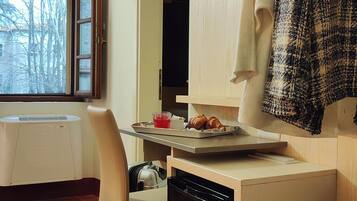 Una cocina compacta con comedor, una ventana con vistas, una silla, una mesita con comida y un perchero para toallas.