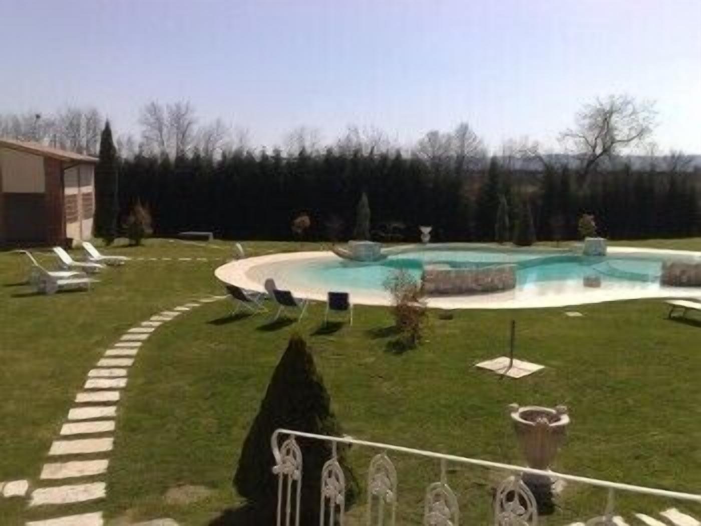 A swimming pool with lounge chairs and a stone pathway.