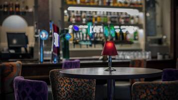 A bar area with a round table, patterned chairs, and a red lamp.