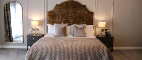 Ein Schlafzimmer mit einem großen Bett, zwei Nachttischen, einem Spiegel und einer Chandelier.