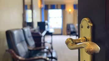 Un vestíbulo de hotel con sillones de cuero, un mostrador de recepción y una puerta con tirador de latón.
