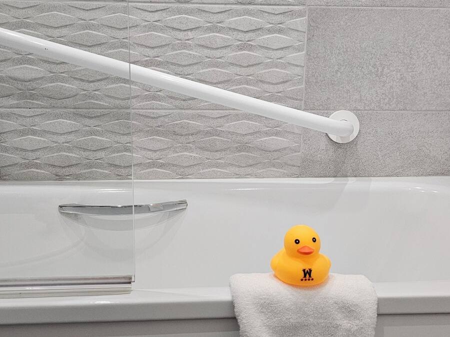 A bathroom with a bathtub, a towel rack, and a rubber duck.