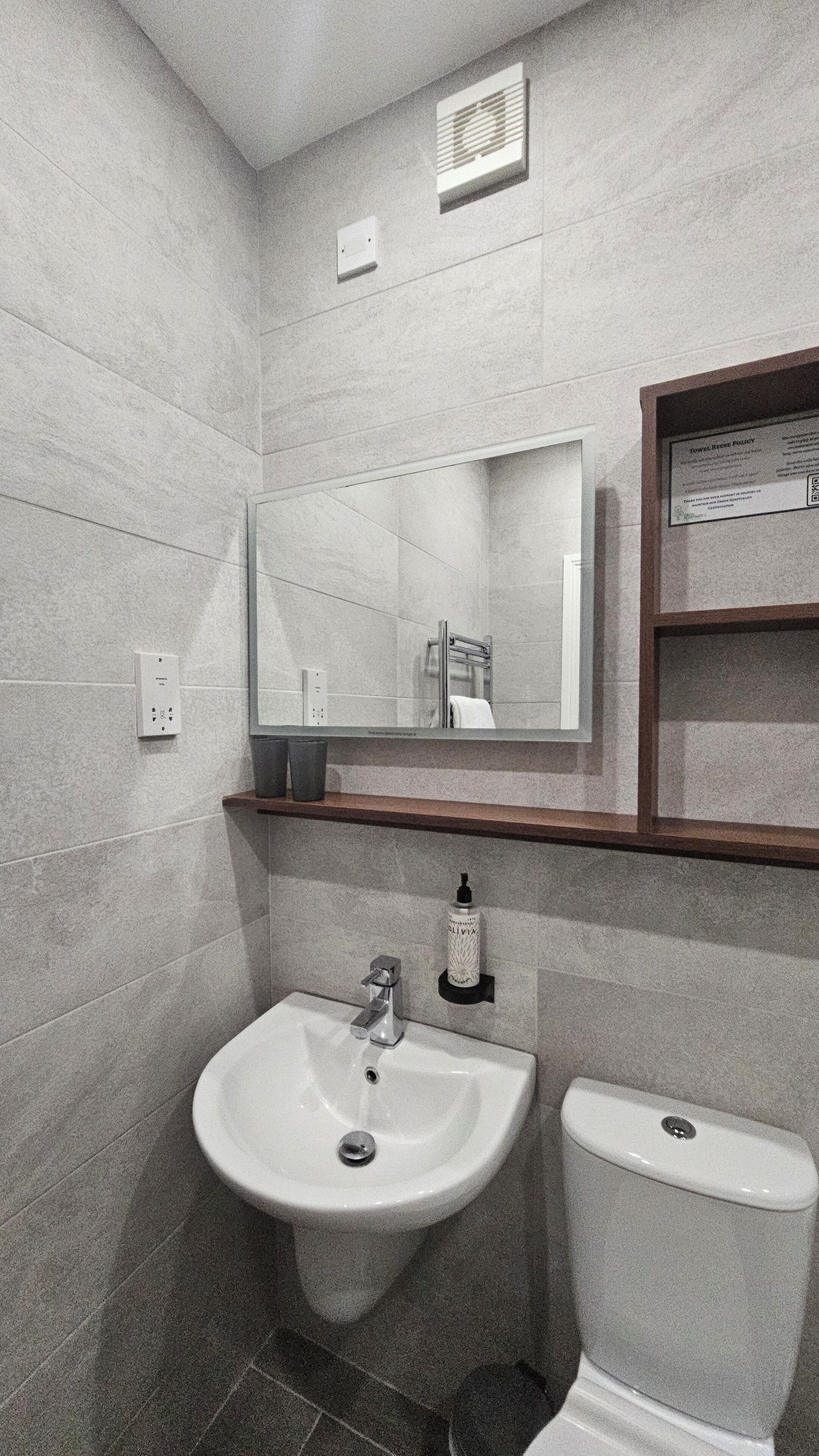 Un baño con un lavabo blanco, un inodoro, un espejo y un toallero.