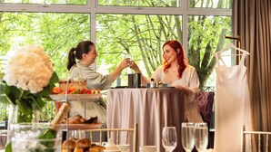 A dining table with a cake, a bottle, and a dress on a hanger.
