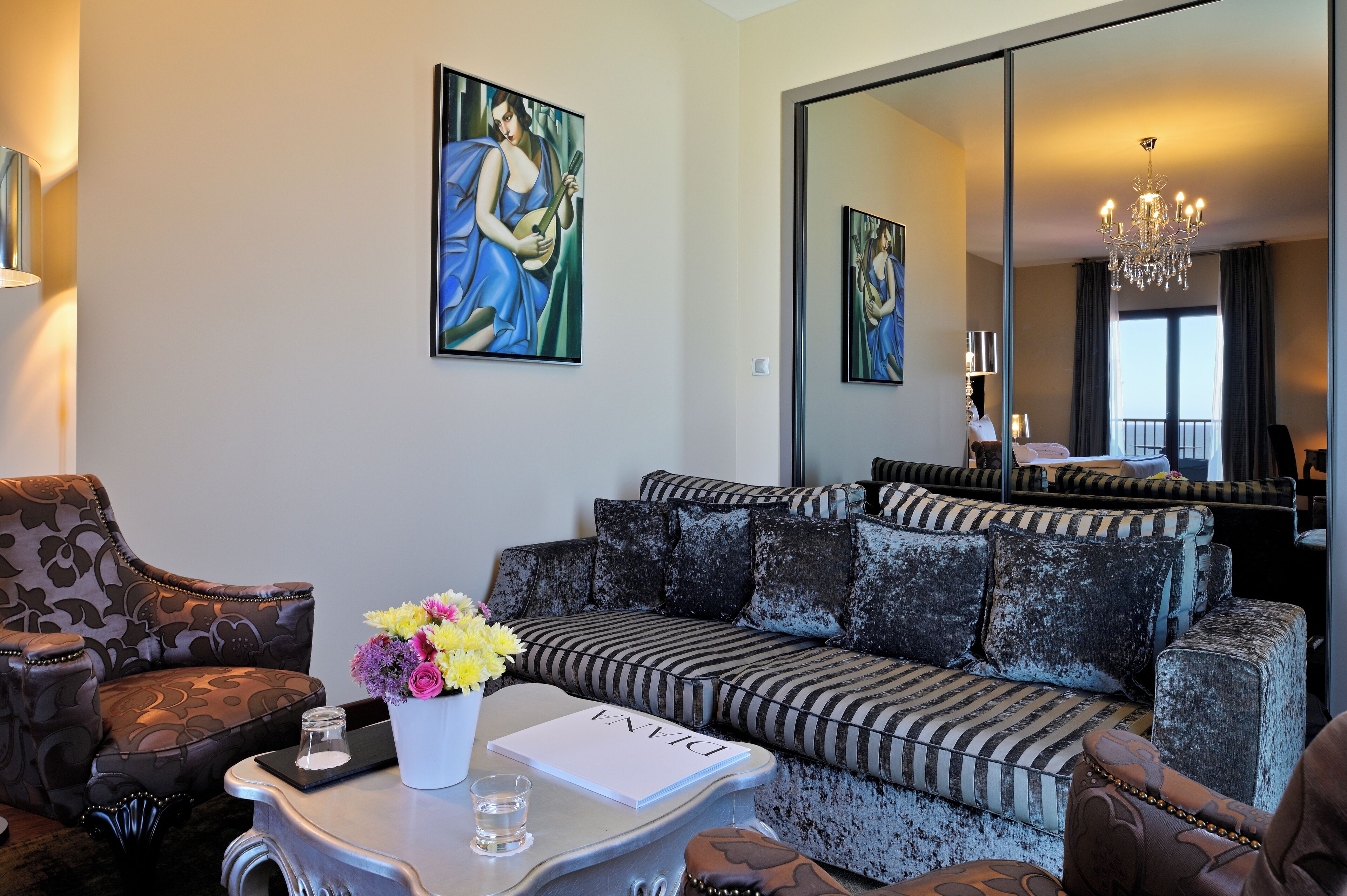 Ein modernes Wohnzimmer mit Sofa, Sesseln, einem Couchtisch mit Blumenvase und einem Gemälde an der Wand.