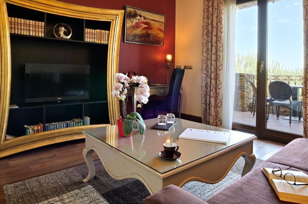 Una sala de estar con un televisor de pantalla plana, una mesa de centro de vidrio, una estantería y un cuadro en la pared.