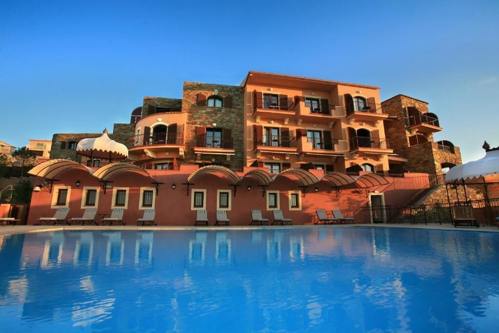 A hotel with a swimming pool, multiple balconies, and a traditional architectural style.