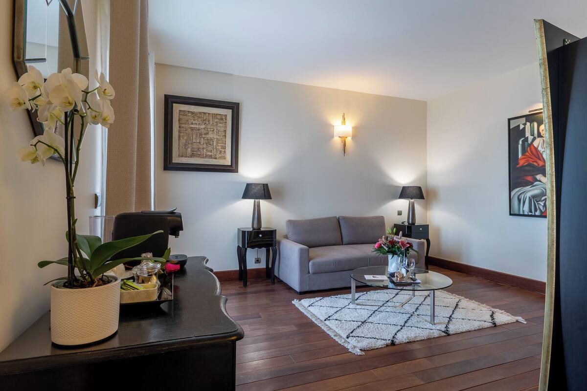 Un salon comprenant un canapé, deux tables d’appoint avec des lampes, une table basse, un tapis et une plante en pot.