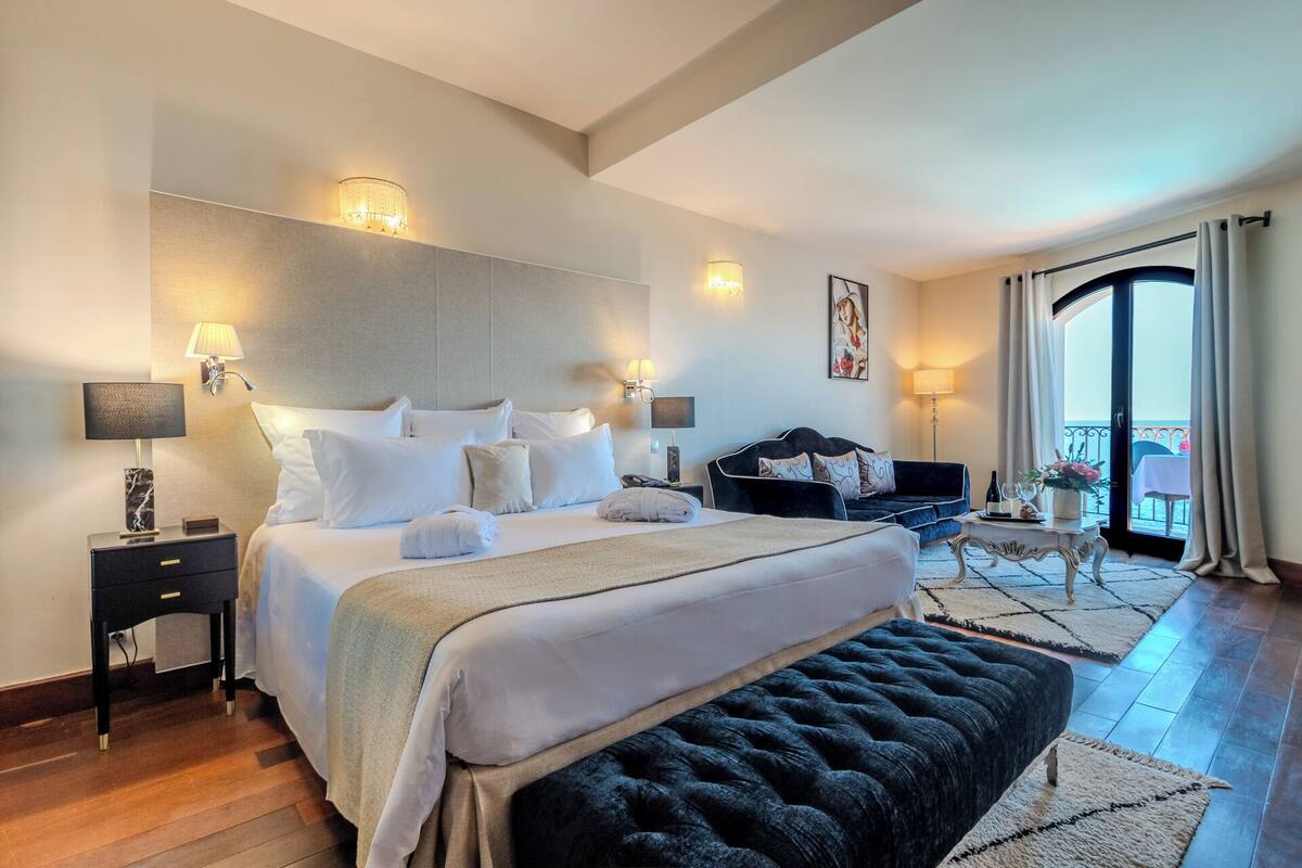 Une chambre d’hôtel avec un grand lit, un canapé, une petite table et un balcon avec vue.