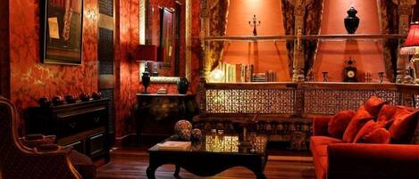 Una habitación ricamente decorada con un sofá rojo, una mesa de centro de madera y un espejo grande.