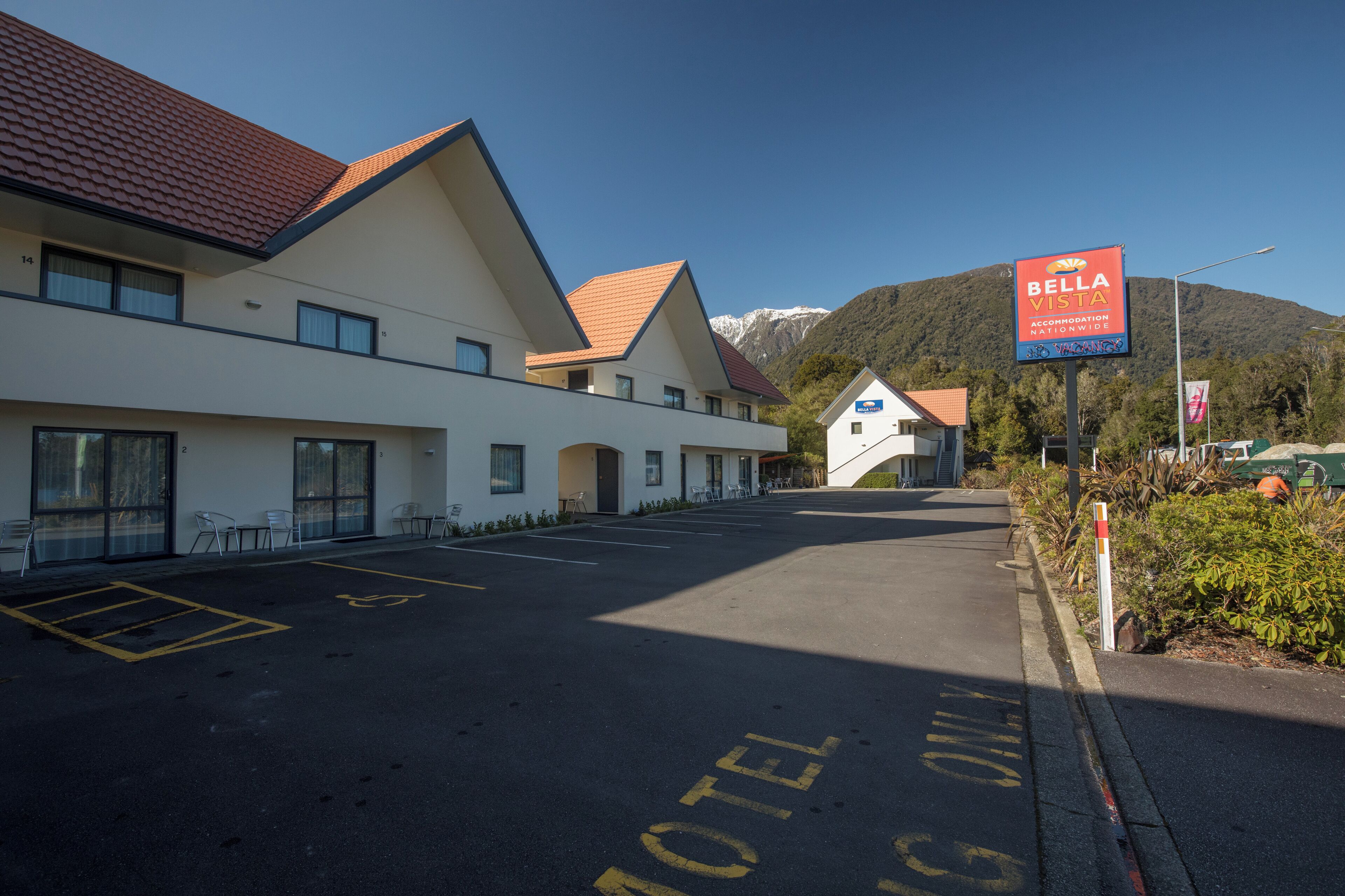 Un hôtel offrant une vue dégagée sur la montagne en arrière-plan, un parking et un panneau indiquant « Bella Vista ».