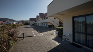 Un edificio moderno con estacionamiento, zona de estar al aire libre y vistas del paisaje circundante.