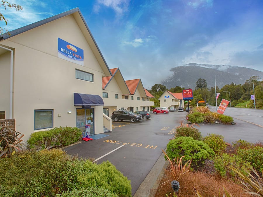 Un motel appelé Bella Vista, composé de plusieurs bâtiments, avec un parking et une montagne en arrière-plan.