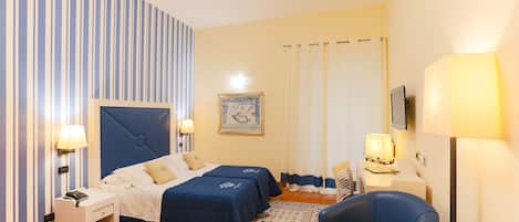 Habitació d'hotel amb dos llits, un escriptori, una cadira i una taula petita.