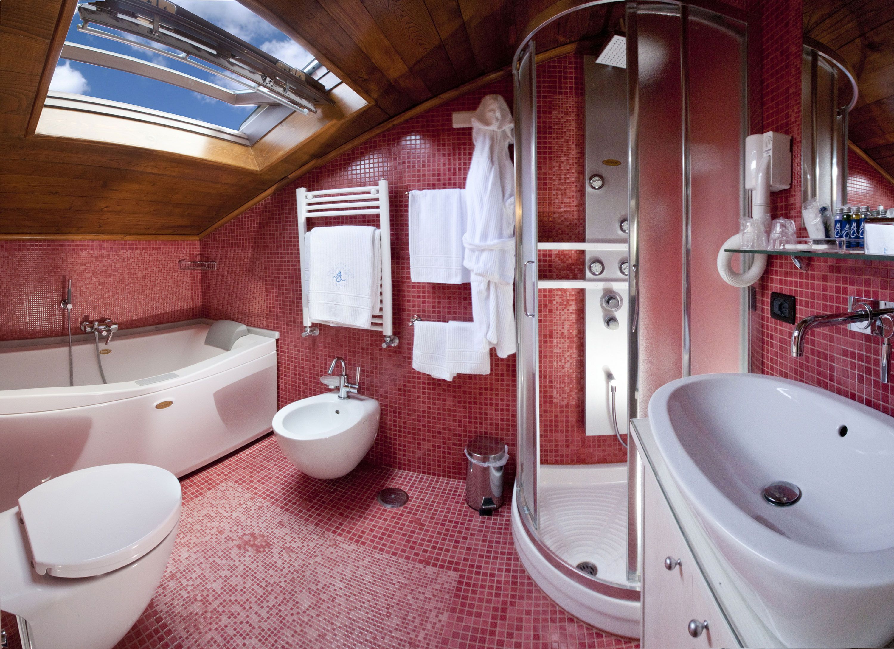 A bathroom with a large bathtub, a separate shower area, a bidet, and a sink.