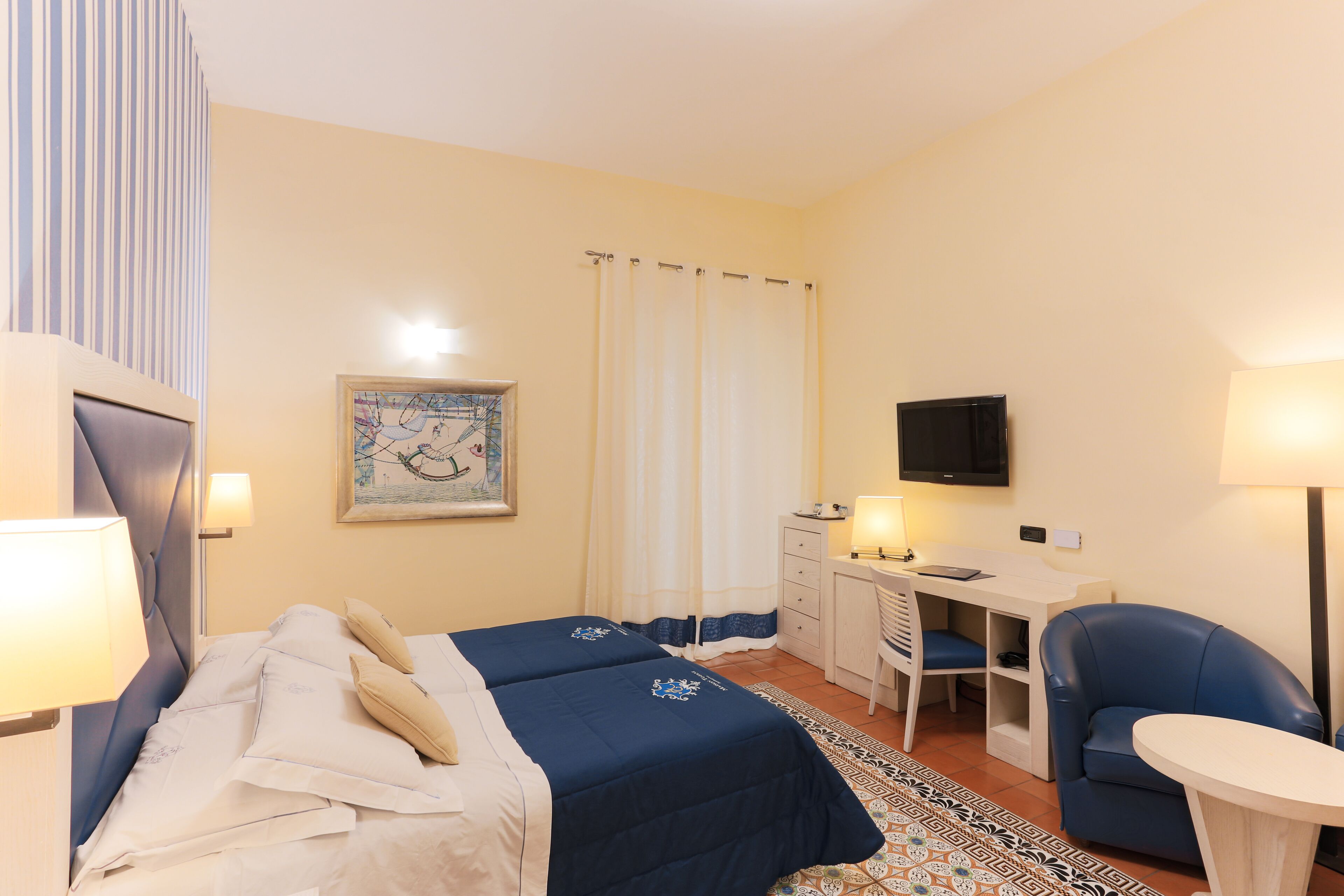 A hotel room with a bed, desk, chair, and a TV.