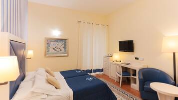 Habitación de hotel con cama, escritorio, silla y televisor.