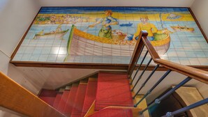 A staircase with a tiled mural depicting maritime scenes. - Hotel Aliai (Sciacca)