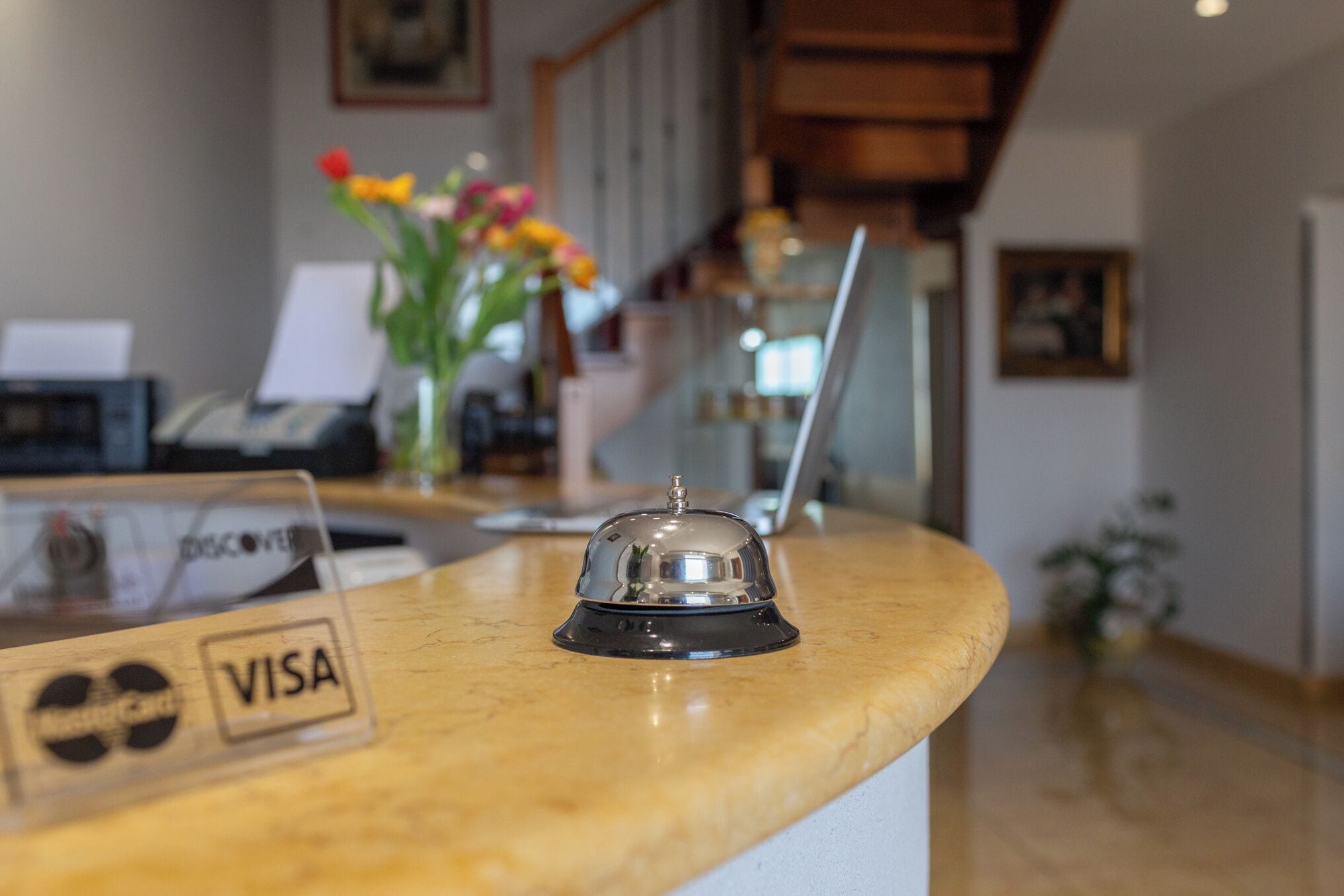 A reception desk with a 'VISA' sign, a telephone, and a decorative vase with flowers.