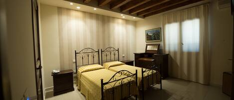 Un dormitorio con dos camas, un aparador, una mesita de noche y un cuadro en la pared.