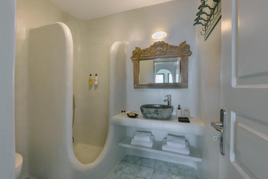 A bathroom with a freestanding bathtub, a sink with a stone basin, a mirror above the sink, and a door with a handle.