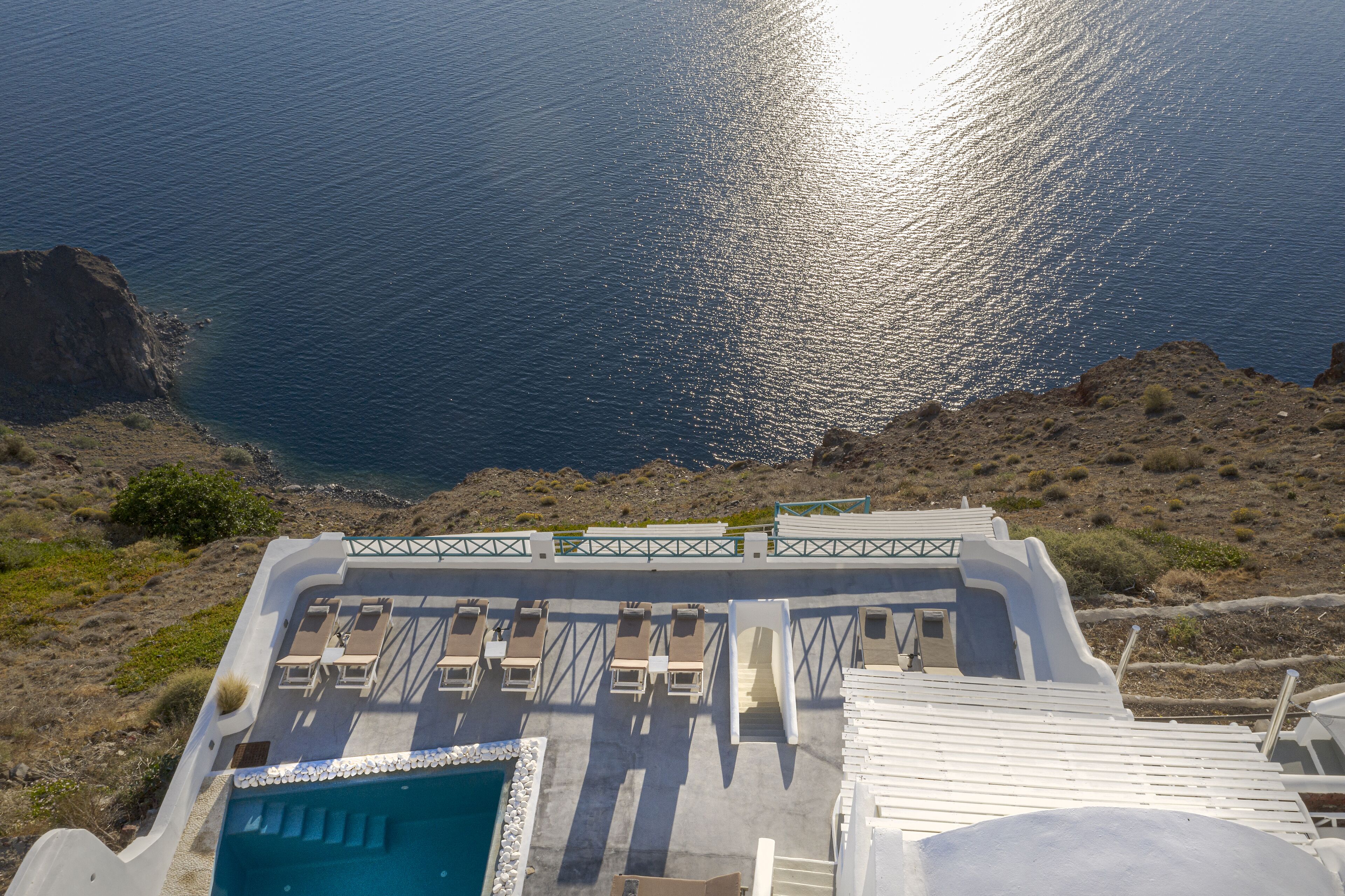 A rooftop pool area with lounge chairs and a view of the sea.