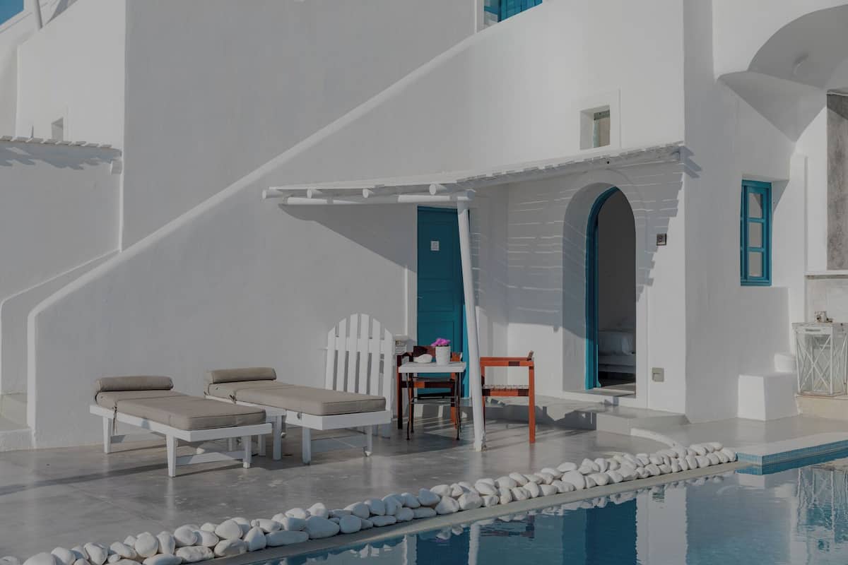 Zona de piscina con sillones, una mesa y una escalera que sube a un nivel superior.