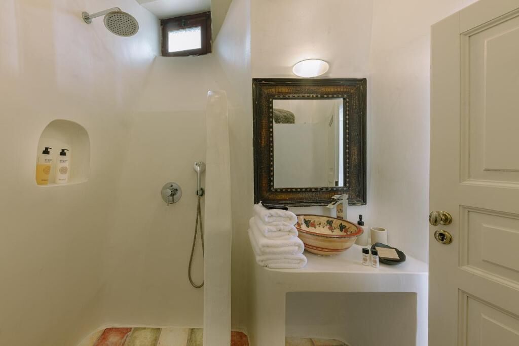 A bathroom with a shower, a sink with a mirror, and toiletries.