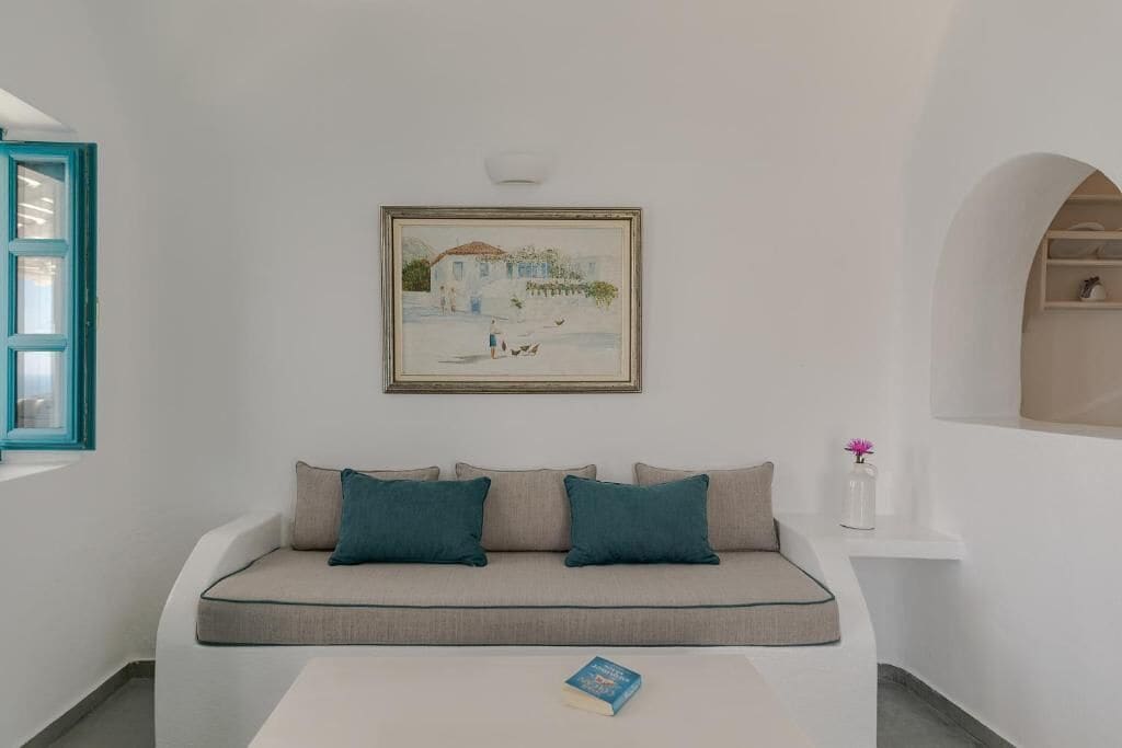 A modern living room with a sofa, a framed painting, and a small table with a book.
