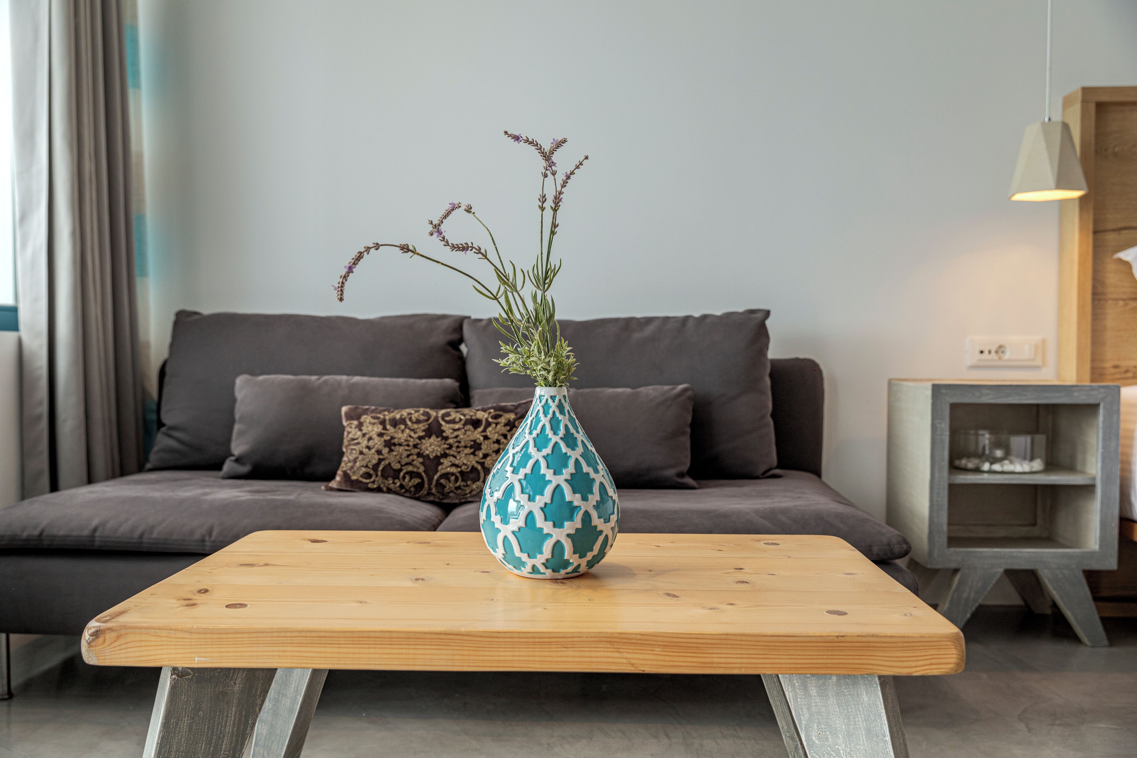 A living room with a sofa, a coffee table, and a decorative vase with plants.