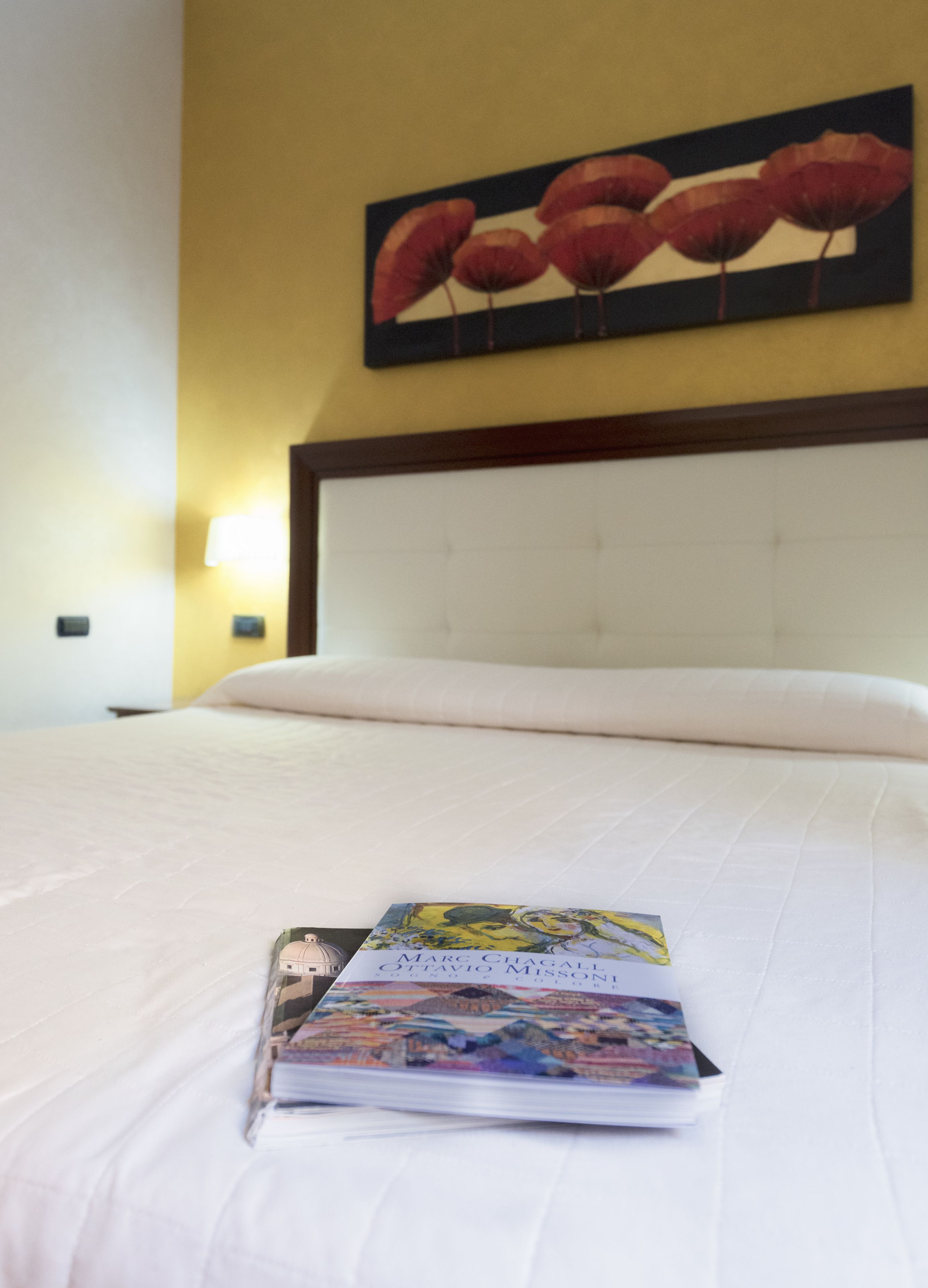 A neatly made bed with a book titled "Marc Chagall" on it.