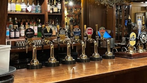 A bar with multiple beer taps, including brands like Beck's, Guinness, and Theakston Best Bitter. - The George Hotel Easingwold (York)