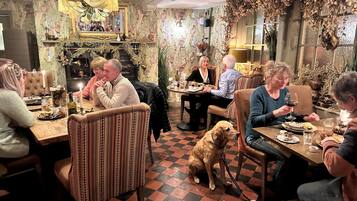 Ein gemütliches Restaurant mit Schachbrettfußboden, gemusterten Tapeten und einem Hund, der am Tisch sitzt.