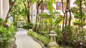A pathway flanked by lush greenery and a traditional stone lantern, leading to a building with balconies. - Le Murraya Boutique Hotel (Koh Samui)