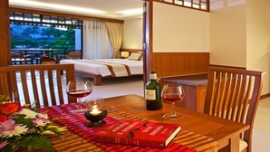 A hotel room with a bed, a dining table with a book and wine, and a view of the outdoors. - Le Murraya Boutique Hotel (Koh Samui)