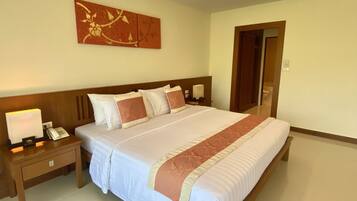 Une chambre d’hôtel avec un grand lit, une table de chevet avec une lampe et un téléphone, et une œuvre d’art accrochée au mur.