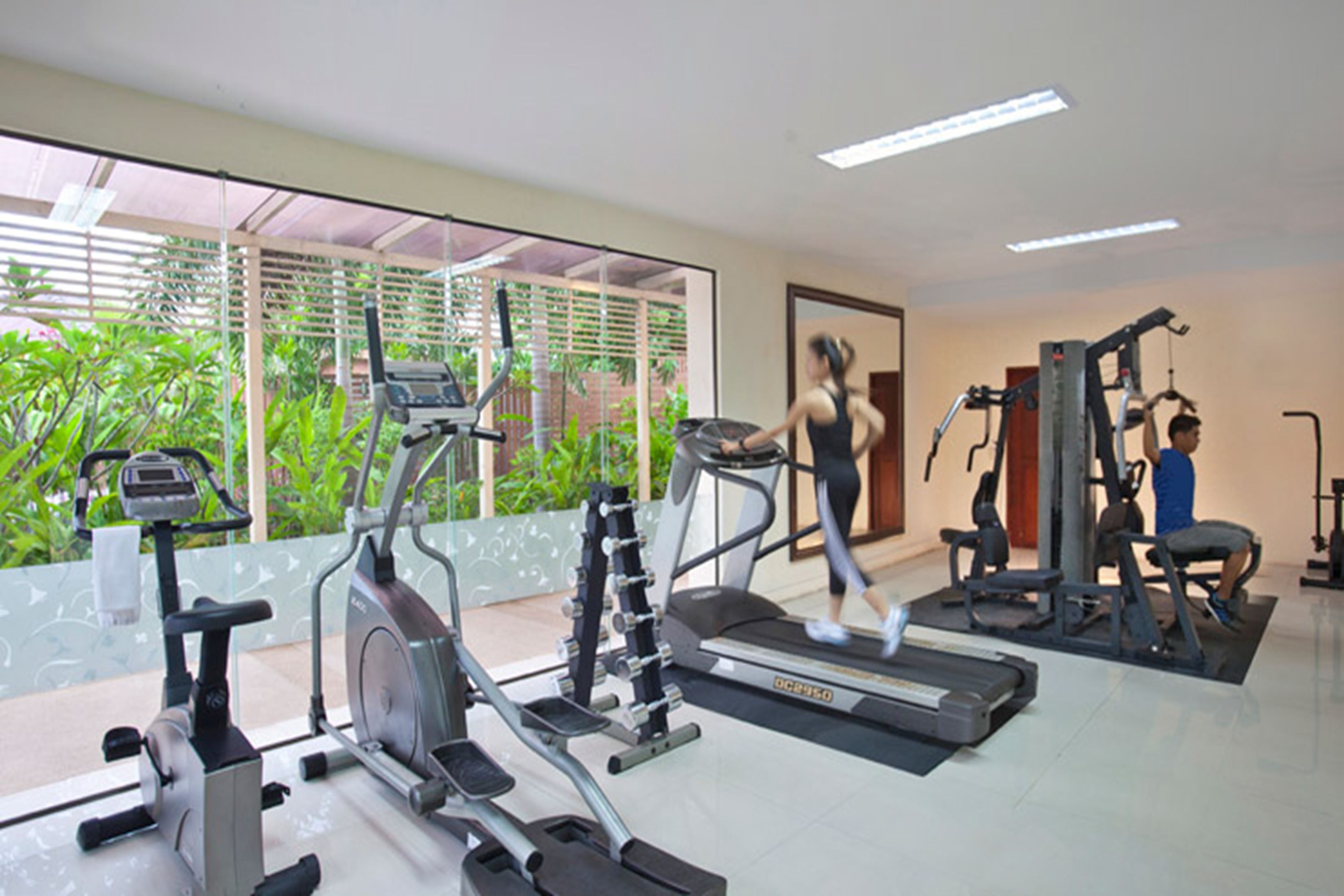 Un gimnasio con cintas de correr, bicicletas estáticas y máquinas de pesas.