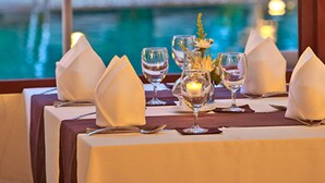 A dining table set for two with a view of a pool and lounge chairs. - Le Murraya Boutique Hotel (Koh Samui)