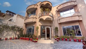Un hôtel doté d’une entrée principale, de plusieurs balcons et de plantes en pot disposées autour de l’entrée.