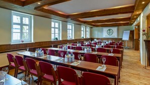 A conference room with wooden beams, red chairs, and tables set for a meeting. - Hotel Zum Harzer (Clausthal-Zellerfeld)