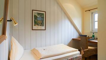 A bedroom with a bed, a chair, a desk, a window, and a painting on the wall.