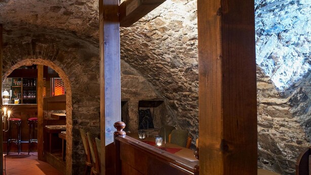 A stone-walled interior with wooden beams, a bar area, and a fireplace. - Hotel Zum Harzer (Clausthal-Zellerfeld)