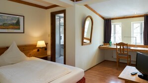 A hotel room with a bed, a desk, a chair, a TV, and a window with curtains. - Hotel Zum Harzer (Clausthal-Zellerfeld)