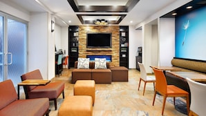 A modern living room with a flat-screen TV, comfortable seating, and a stone-tiled floor. - Fairfield Inn & Suites by Marriott New York ManhattanChelsea (New York)