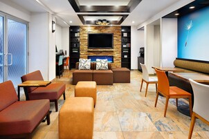 Una sala de estar moderna con un televisor de pantalla plana, asientos cómodos y piso de baldosas de piedra.