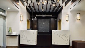 A reception area with marble counters, a dark wooden reception desk, and pendant lighting. - Fairfield Inn & Suites by Marriott New York ManhattanChelsea (New York)