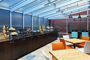 A modern kitchen with a central island, wooden cabinets, and a glass enclosure.