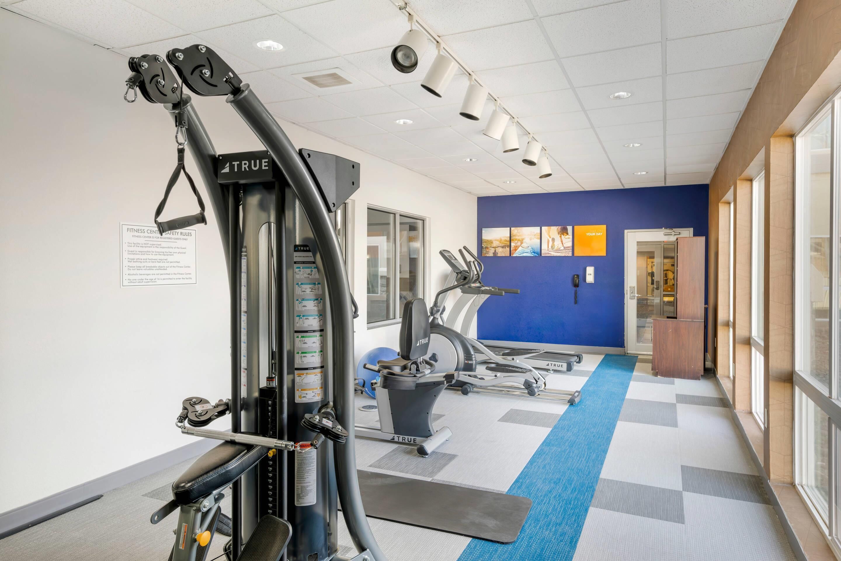 A fitness center with exercise equipment, a blue wall, and a checkered floor.