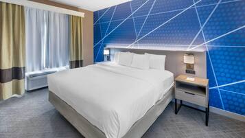 A hotel room with a large bed, a nightstand with a lamp, and a wall with a geometric pattern.